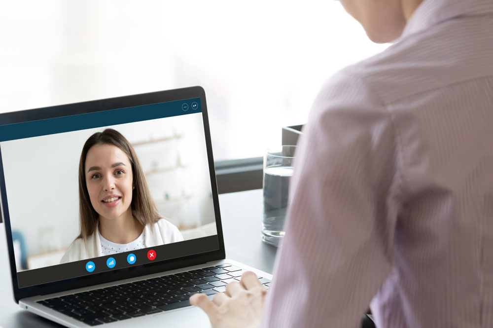 Schmuckbild:Schulterblick auf einen Laptop während einer online Beratung. Die Beraterin befindet sich mit einem jungen Mädchen im Gespräch.